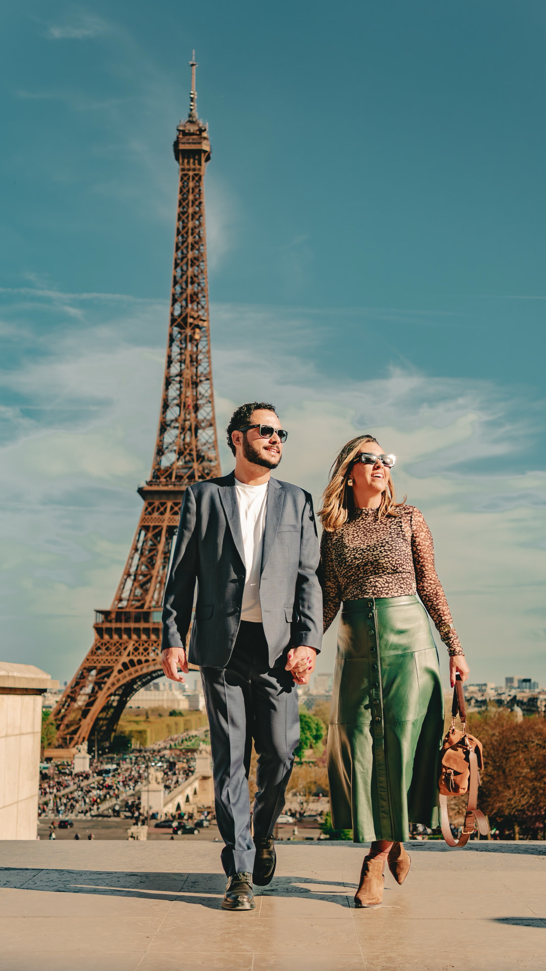 Karen e Vitor caminhando de mãos dadas em frente à Torre Eiffel, em Paris